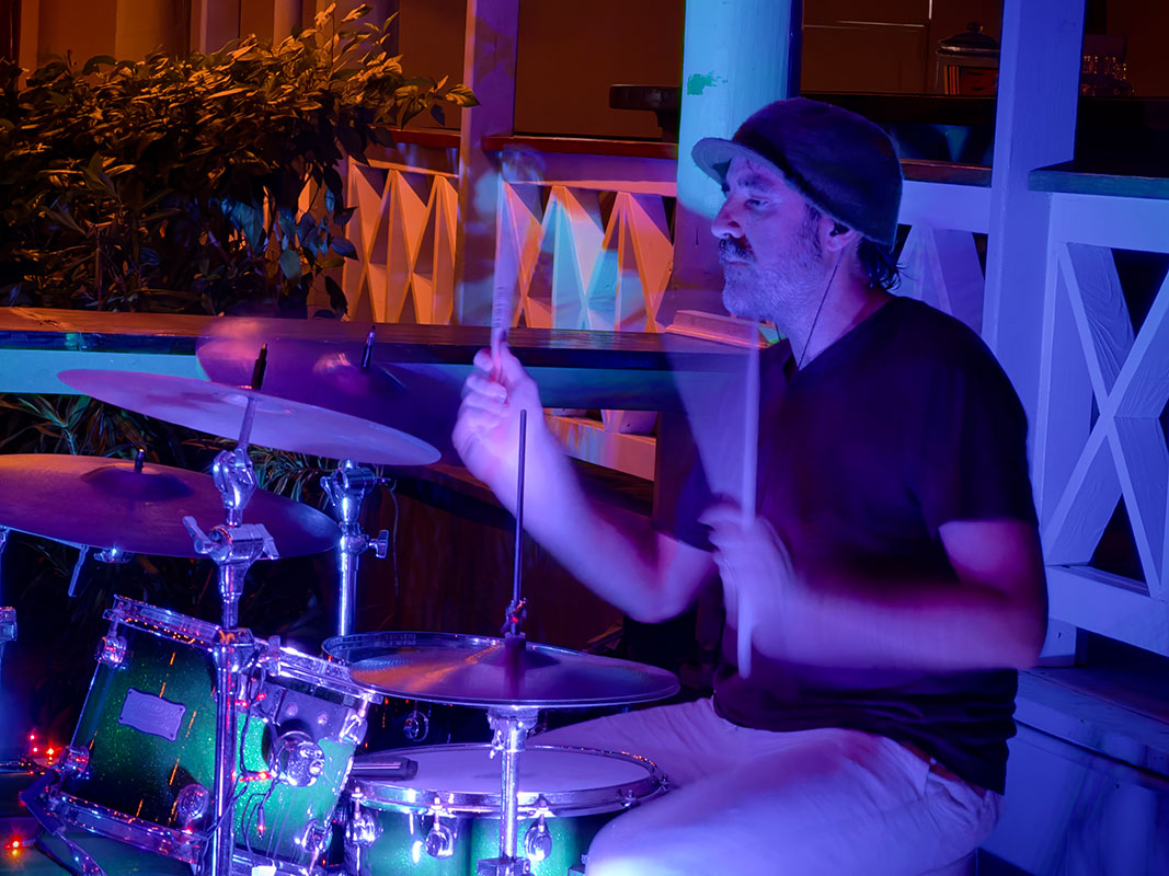 Heat Seekers drummer Tim behind the kit at Hull Bay Hideaway St Thomas with blue and purple stage lighting